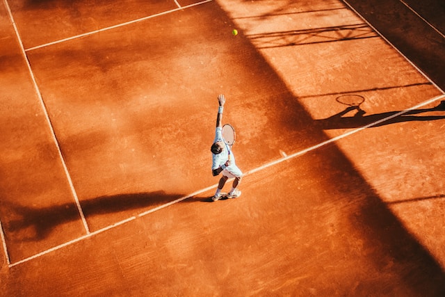 テニスコートでボールを上に投げてサーブをしようとしている男性